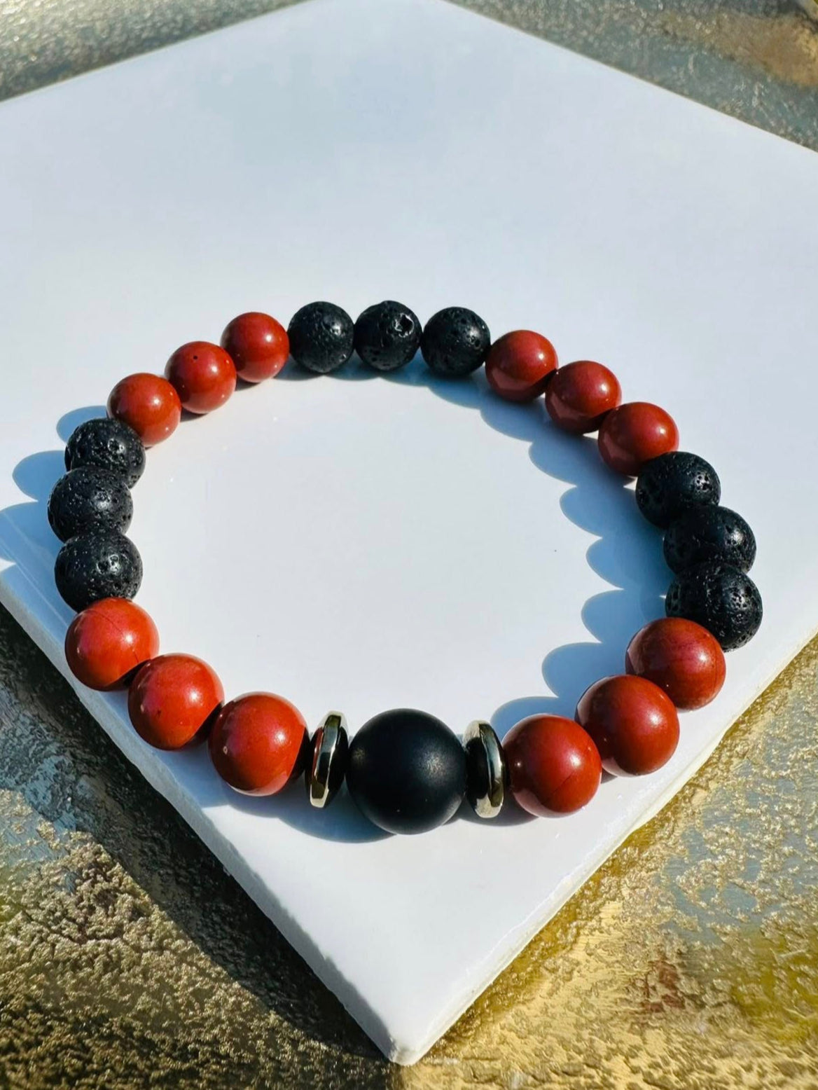 A bracelet of contrast and calm—porous black lava beads meet smooth reddish-brown warmth, centered by a matte black bead and two metallic rings. Grounded, earthy, and quietly powerful.